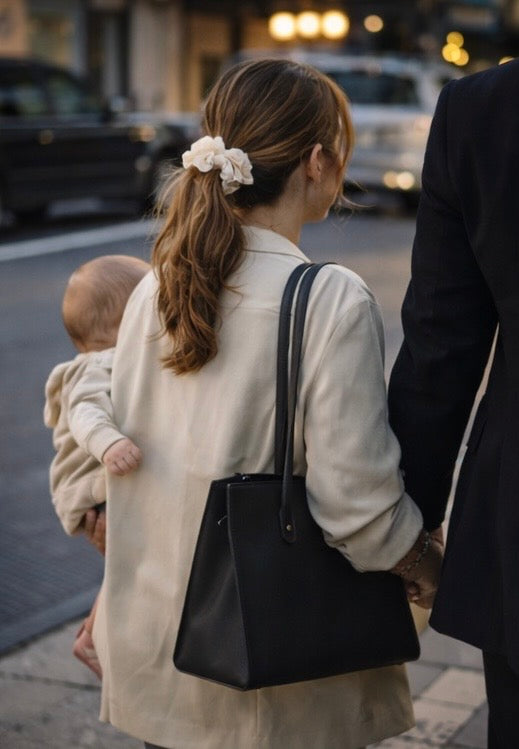 Woman in business attire holding her baby on her hip while wearing a BUNLUV scrunchie, styled for everyday movement and simple routines.