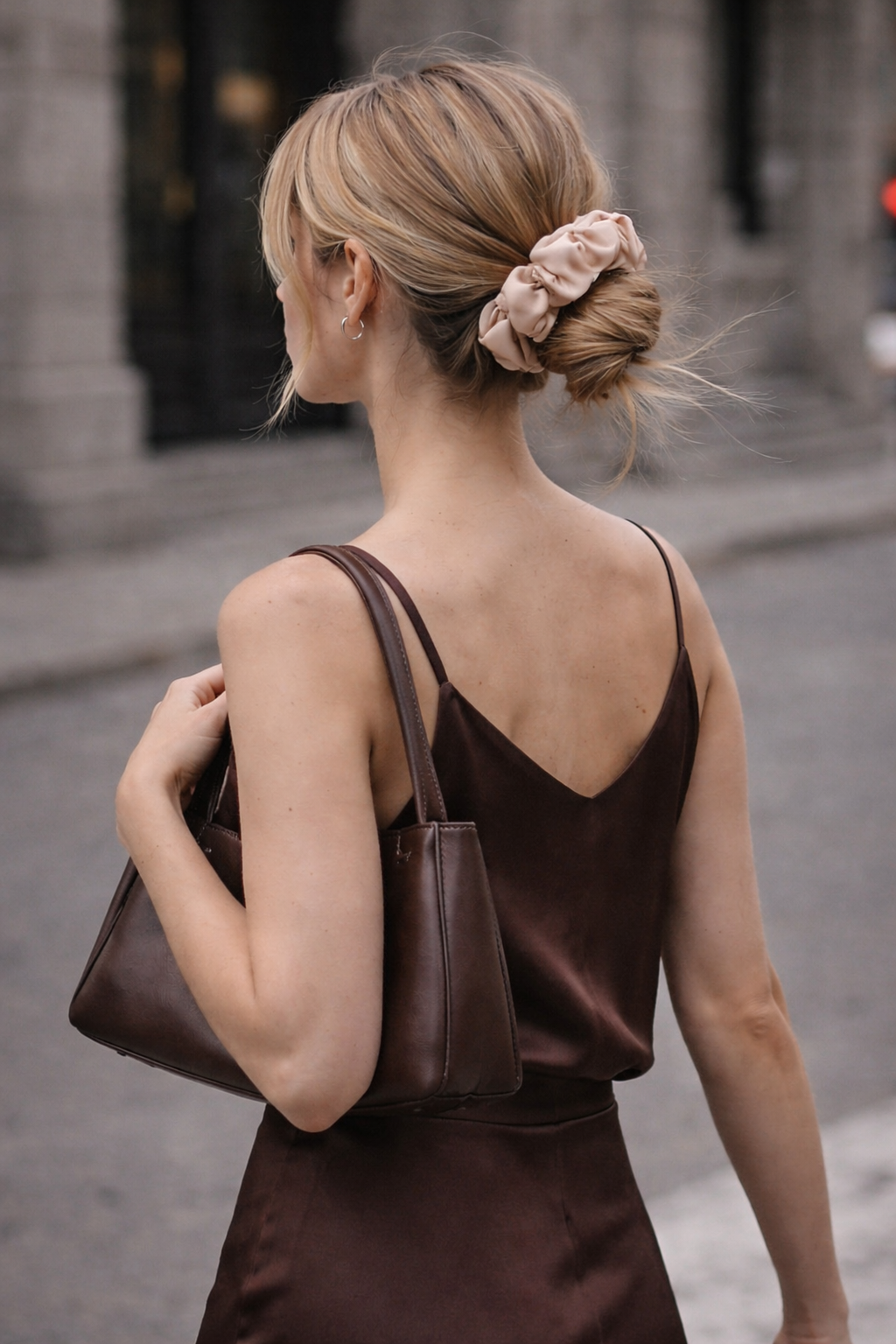 Woman in a brown dress with a brown handbag, walking on a street wearing a nude silk bunluv scrunchie