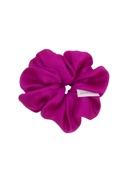 Pink scrunchie with a brand label on a white background