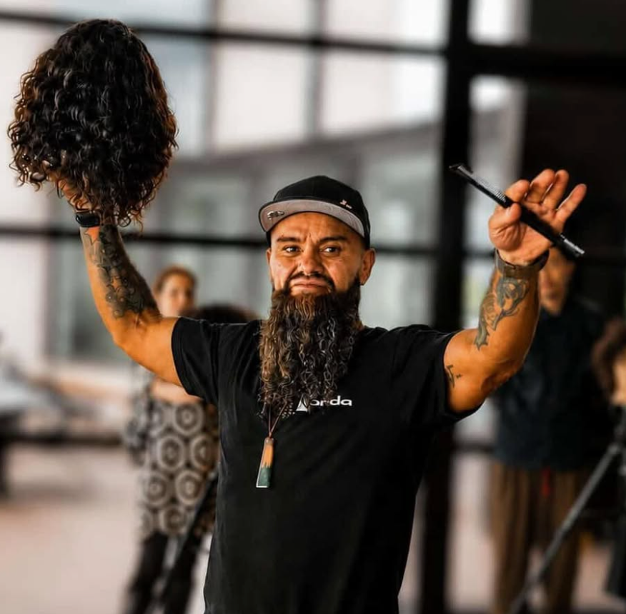 David corry hair dresser holding a wig and styling tool educating on textured hair