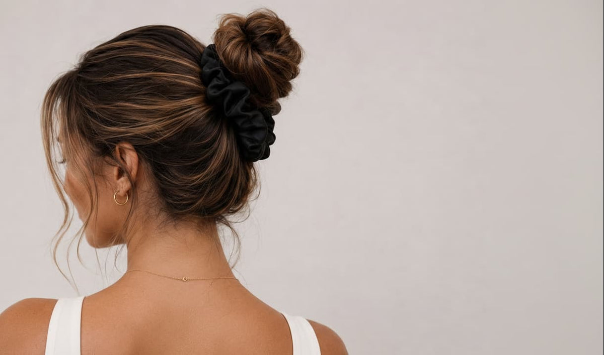 Woman with a stylish hair bun using a bunluv silk smartcore black spiral scrunchie on a plain background