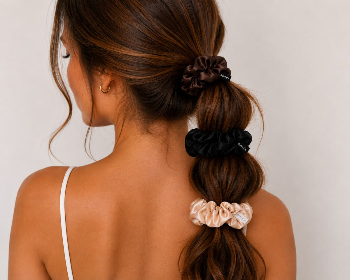 Woman with styled hair usingset of three bunluv smartcore scrunchies on a plain background